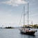 A schooner carries passengers toward a lighthouse in a narrow channel